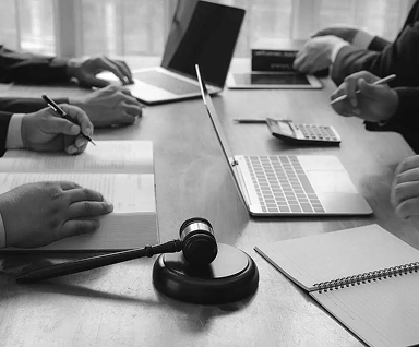 Uma mesa com computadores e pessoas trabalhando.